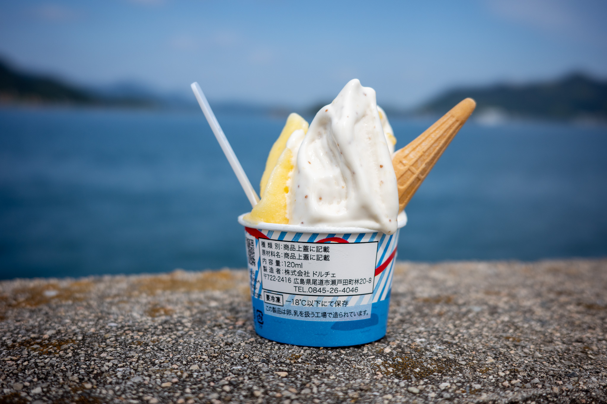 青いカップのジェラートとコーン、海の背景