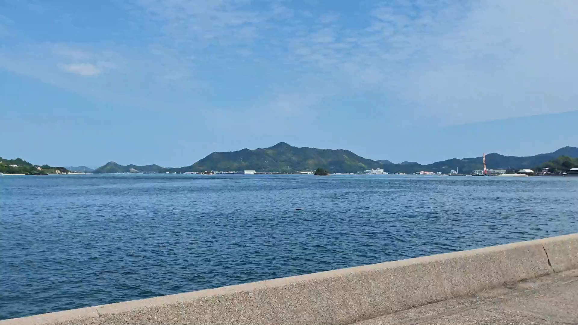 海面と対岸の山並み、海沿いの道。